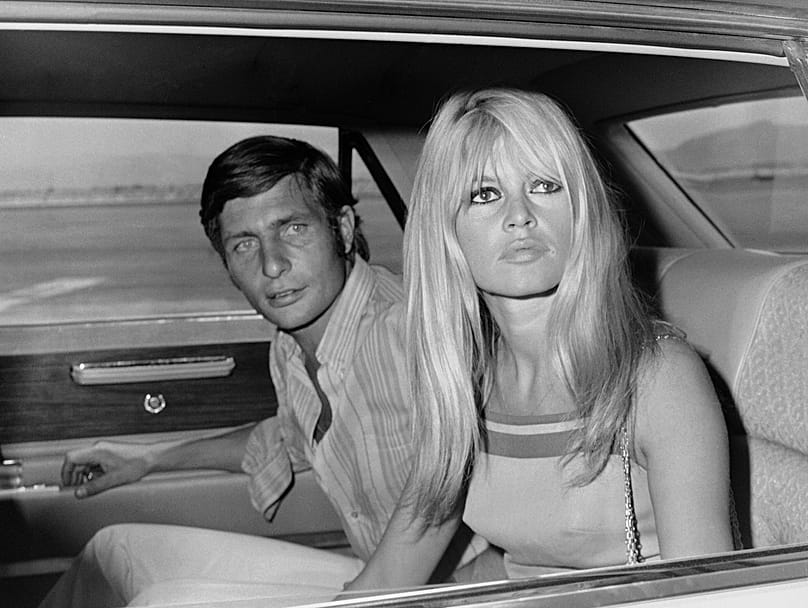 French film actress Brigitte Bardot and her husband Gunter Sachs pose just before boarding a chartered airplane on their honeymoon in Las Vegas on July 14, 1966.