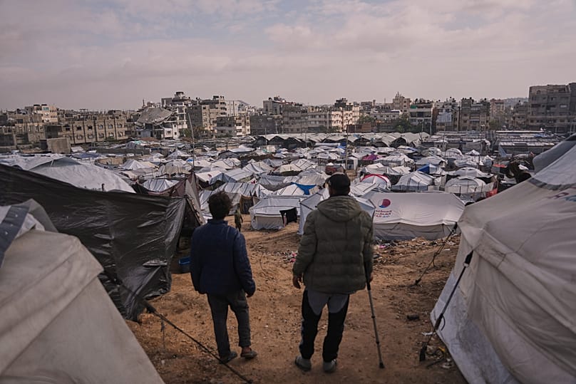 Palestinians look over makeshift tents of a camp for displaced people set up in an area of Gaza City, 29 December, 2025