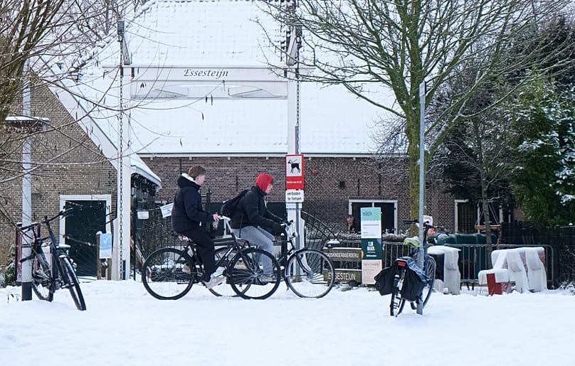 Two Dutch youth cycle carefully along an ice-covered bike path near a children's petting farm in the town of Voorburg, 6 January, 2026