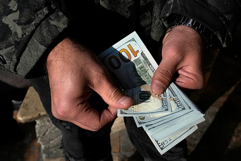 A man counts US dollars at Ferdowsi Street in downtown Tehran, 18 December, 2024