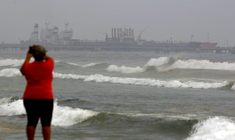A woman takes a picture of the dock of El Palito refinery near Puerto Cabello, Venezuela.