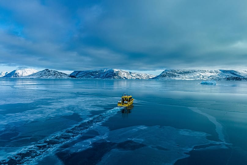 A boat sails though a frozen sea inlet outside of Nuuk, 6 March, 2025