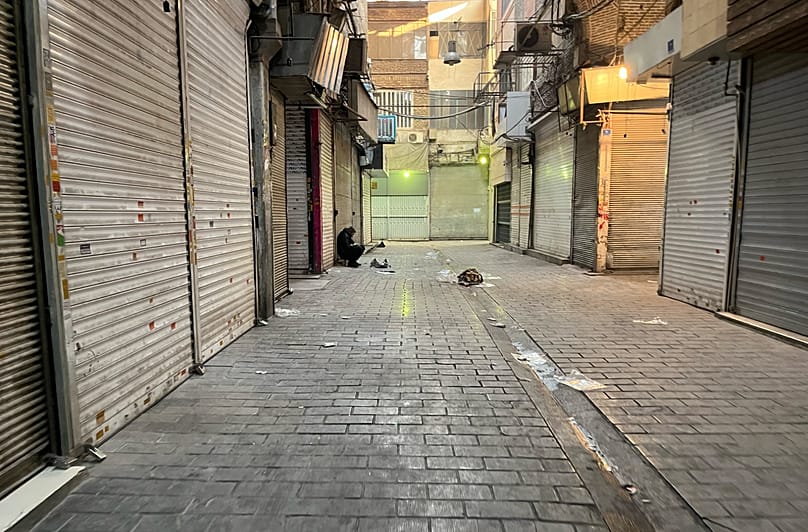 A man sits as shops are closed during protests in Tehran's centuries-old main bazaar, 6 January, 2026