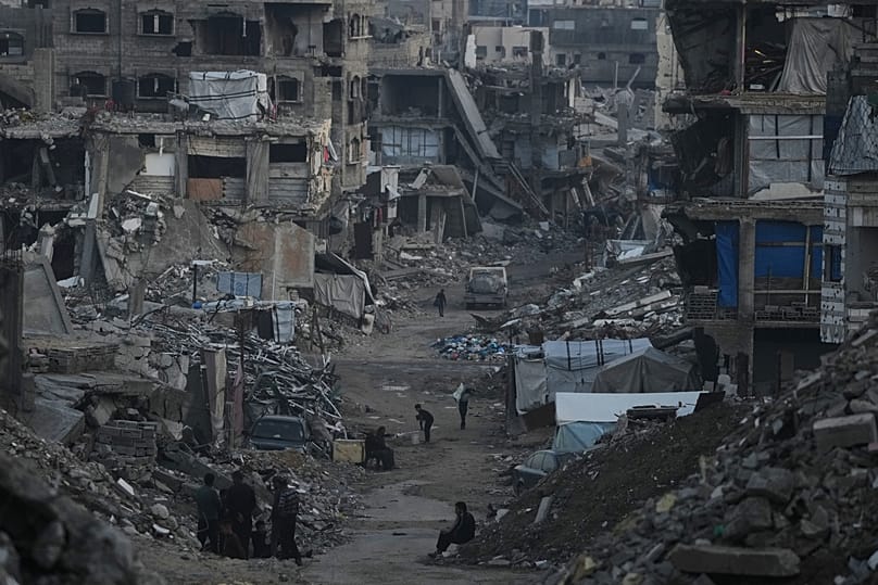 Palestinians walk amid buildings destroyed by Israeli air and ground operations in Gaza City, 6 January, 2026