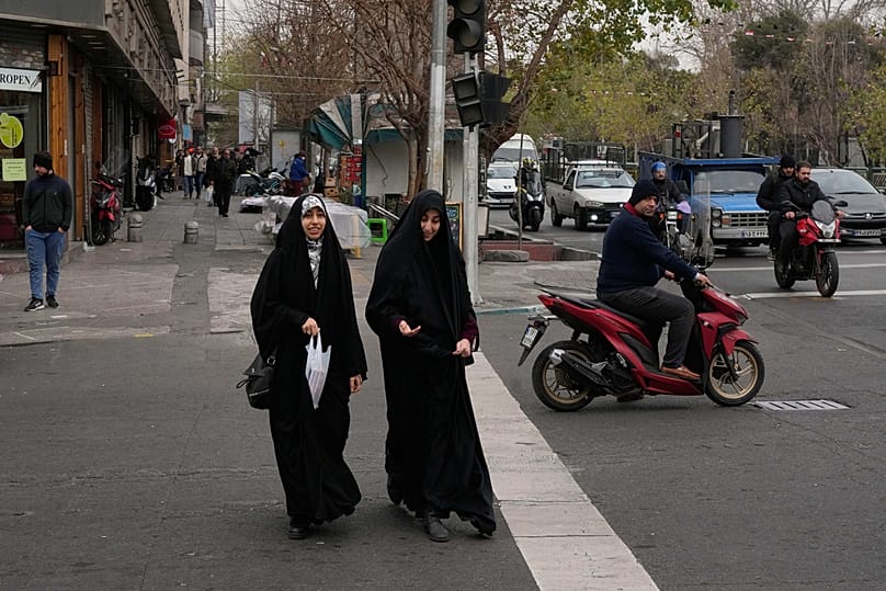 Women cross an intersection in downtown Tehran, Iran, Thursday, Jan. 15, 2026