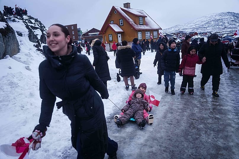 A woman pulls her children on a sled during a protest against Trump's policy towards Greenland in front of the US consulate in Nuuk, Greenland, Saturday, Jan. 17, 2026