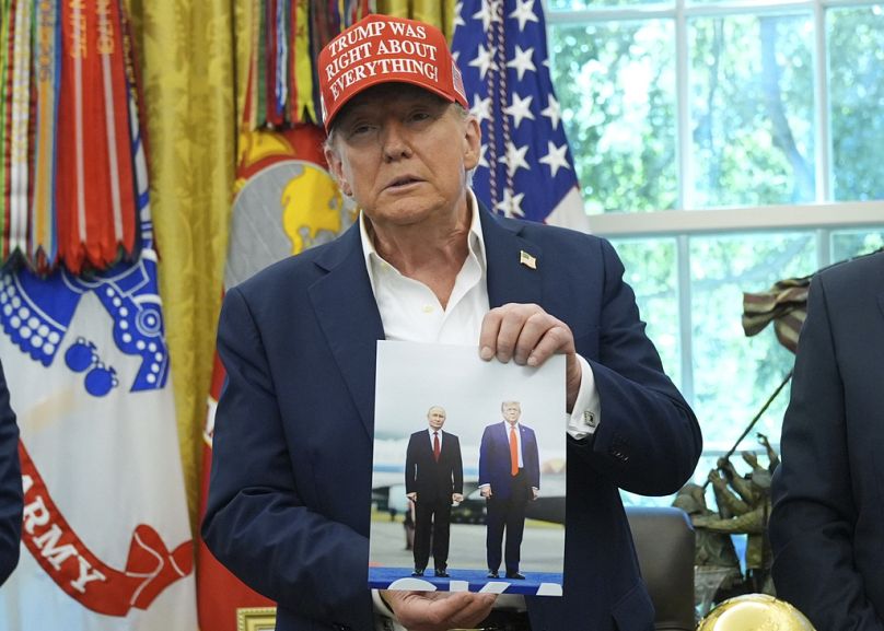Trump holds a photo of himself with Russian President Vladimir Putin in the Oval Office of the White House, 22 August 2025, in Washington