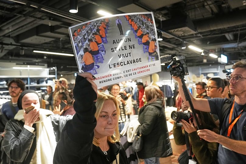 A protester holds a placard reading "No style worth slavery" in the BHV department store as fast fashion Shein opens its first physical store, Wednesday, 5 November 2025.