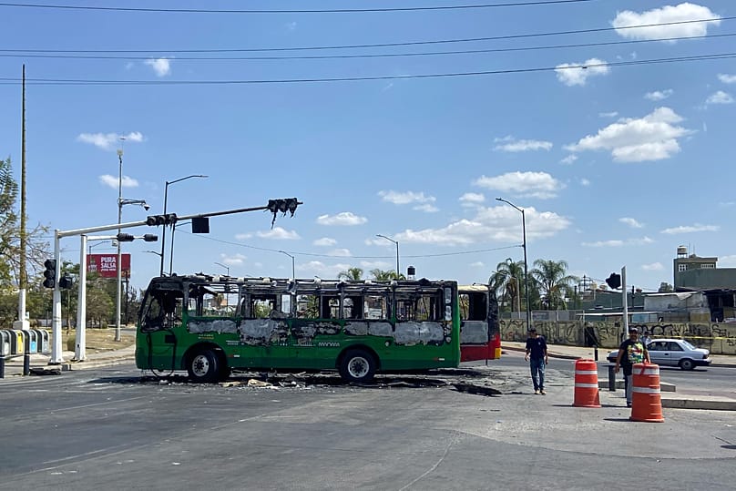 Pedestrians walk past charred buses that were set on fire, on a road in Guadalajara, Jalisco state, Mexico, Feb. 22, 2026, after the death of cartel leader "El Mencho."