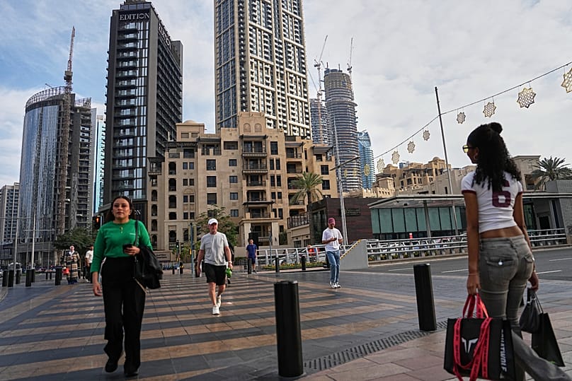 People cross a street in downtown Dubai, 7 March, 2026