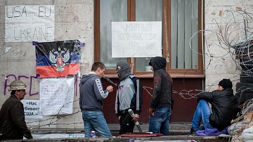 Pro-Russian activists on 2 May 2014 in Donetsk (Ukraine) in front of the regional administration building holding a flag of the self-proclaimed "People's Republic"
