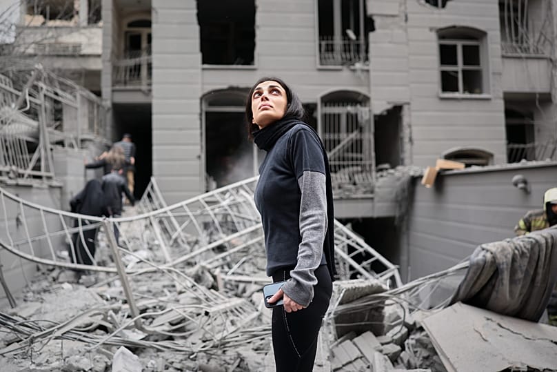 A woman looks up at the site of a strike that hit a residential building in Tehran, 28 March, 2026