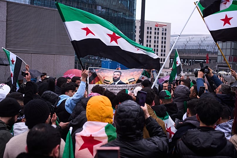 People supporting Syrian President Ahmad al-Sharaa celebrate ahead of a meeting with German Chancellor Friedrich Merz opposite the chancellery in Berlin, 30 March, 2026
