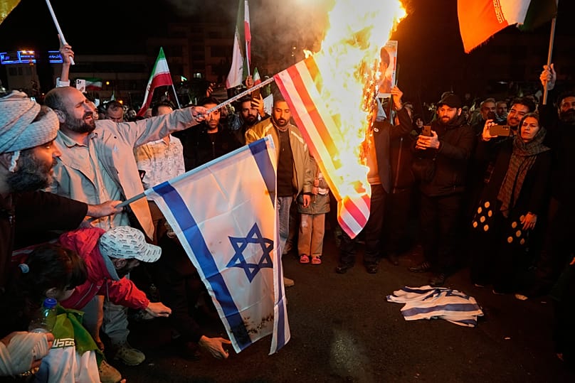 Iranian pro-government demonstrators burn the U.S. and Israeli flags during a gathering after announcement of a two-week ceasefire, Tehran, Iran, Wednesday, April 8, 2026.