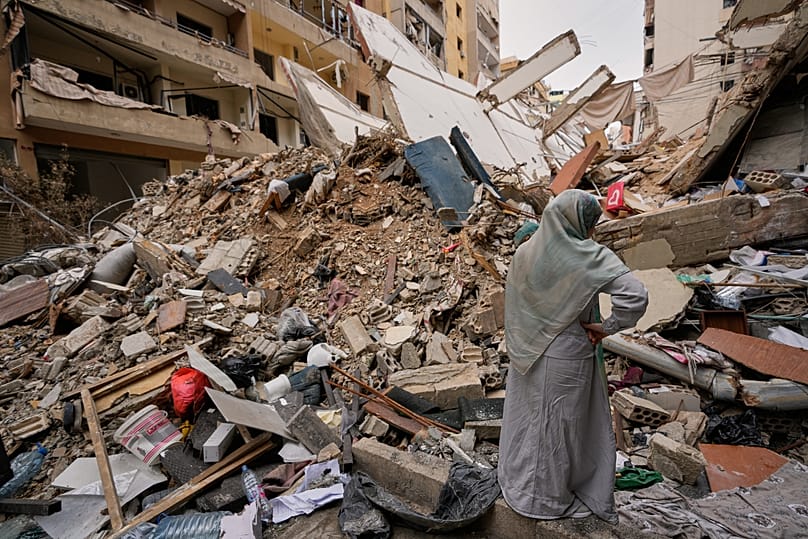 A woman stands by the rubble of a destroyed building in Beirut's southern suburbs, 20 April, 2026
