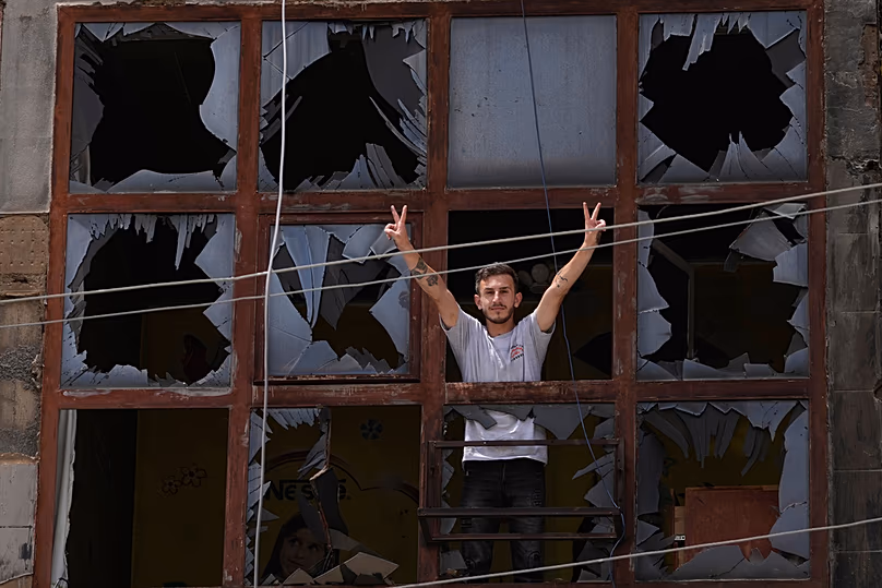 Man flashes victory sign through the shattered window of a damaged apartment following a truce between Israel-Hezbollah in Nabatiyeh, southern Lebanon, Monday, June 22, 2026