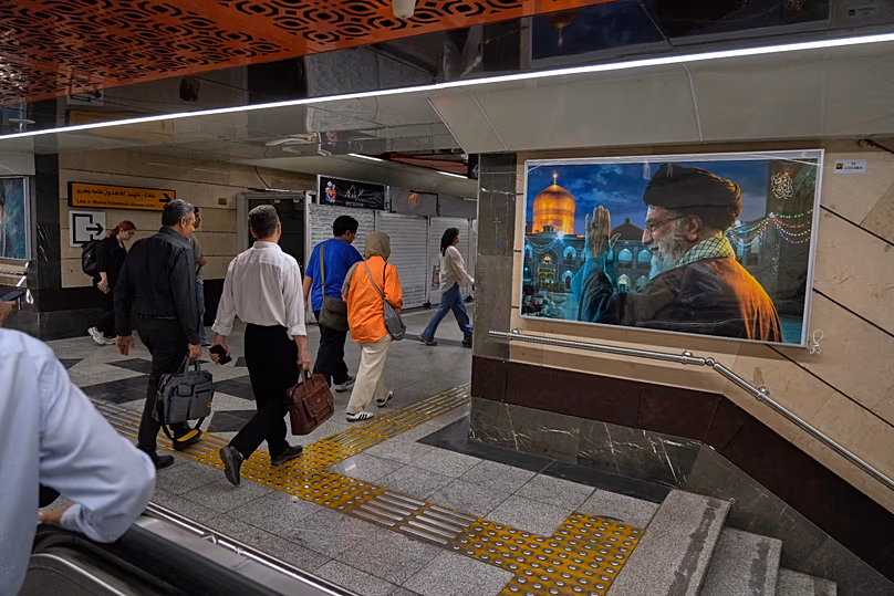 FILE: People walk past a portrait of the slain Ayatollah Ali Khamenei, killed in US and Israeli strikes on 28 February, in a metro station in Tehran, 8 June 2026