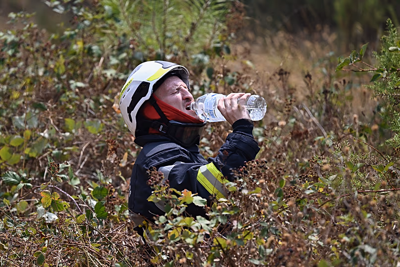 A firefighter takes a drink of water while battling a wildfire near Le Temple, outside, Bordeaux, France, Sunday, July 26, 2026