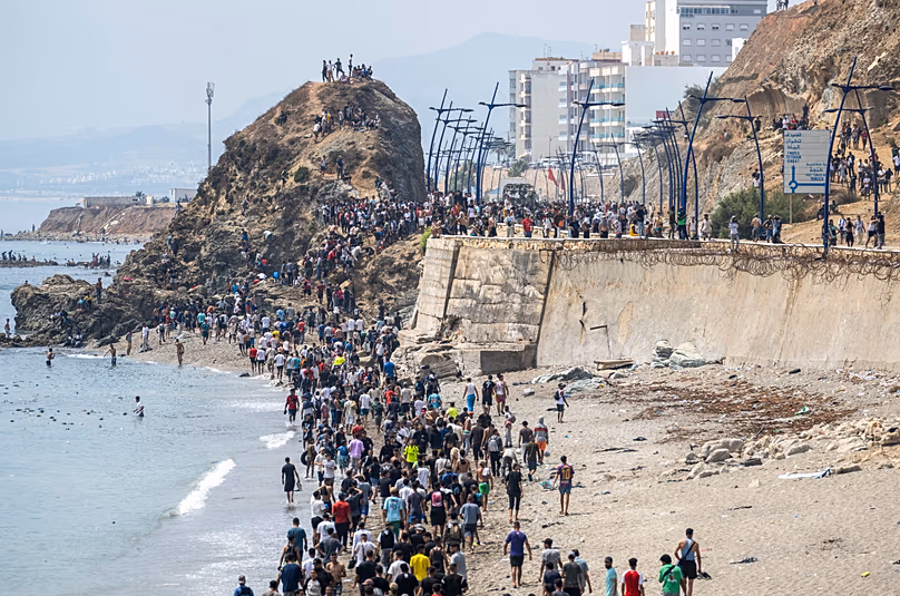People walk on a beach after attempting to cross from the Moroccan northern town of Fnideq to the Spanish enclave of Ceuta, Friday, July 31, 2026.