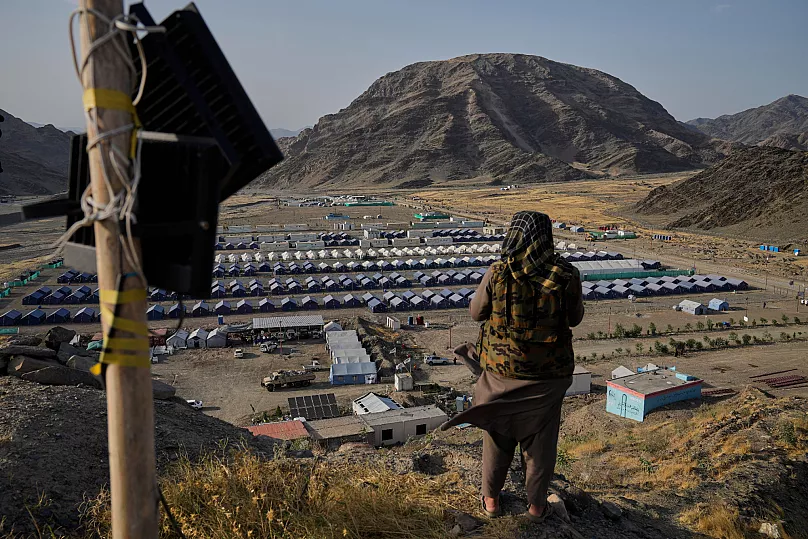 A Taliban fighter stands on a hill overlooking a camp housing Afghan refugees in Torkham, 31 May, 2025