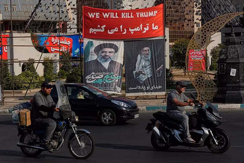 Vehicles drive past a banner reading in English and Farsi, "We will kill Trump" in Tehran, 10 August, 2026