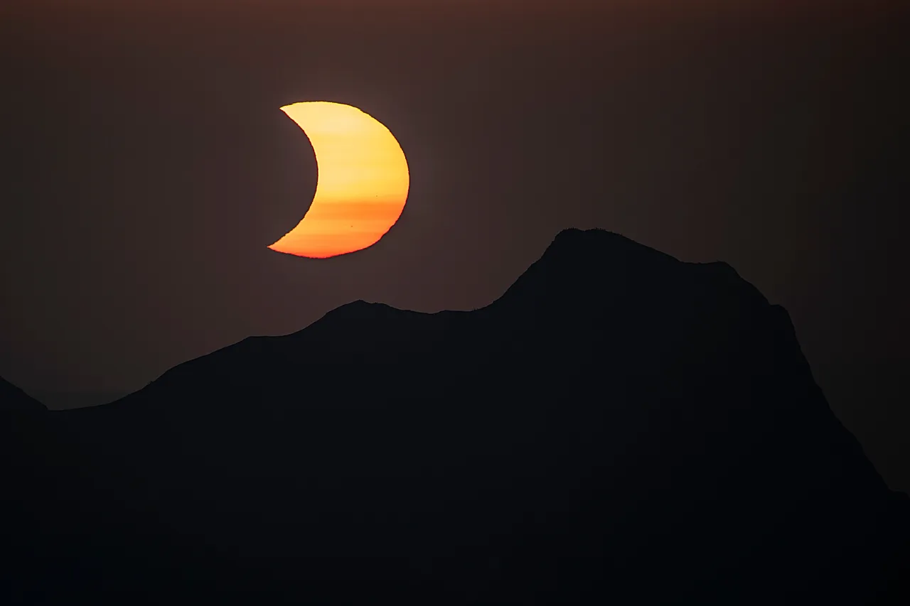 The moon obscures the sun above the summit of Gantrisch during a partial solar eclipse - seen from the summit of the Niesen mountain in the Bernese Oberland in Switzerland