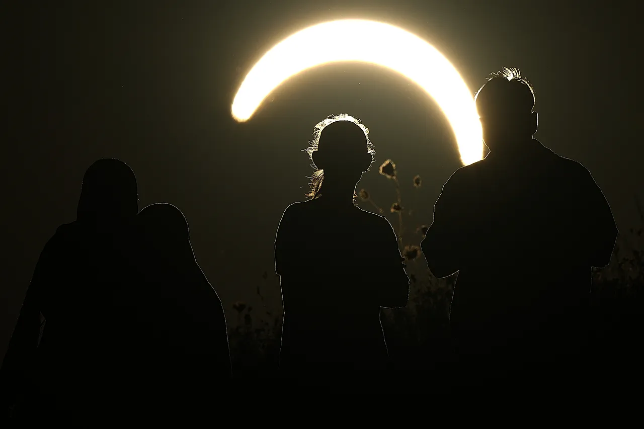 People observe a partial solar eclipse at Northala Fields in London