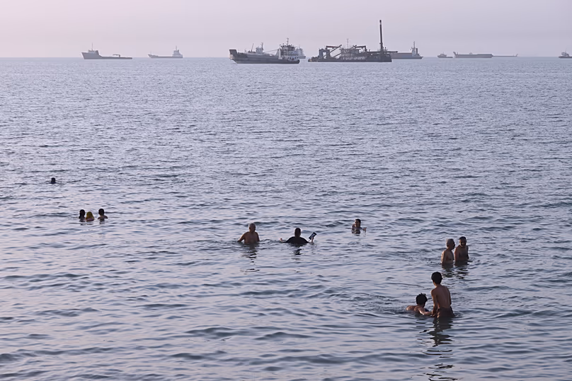 Residents swim as cargo and commercial vessels are anchored in the Strait of Hormoz off Bandar Abbas, 6 August, 2026