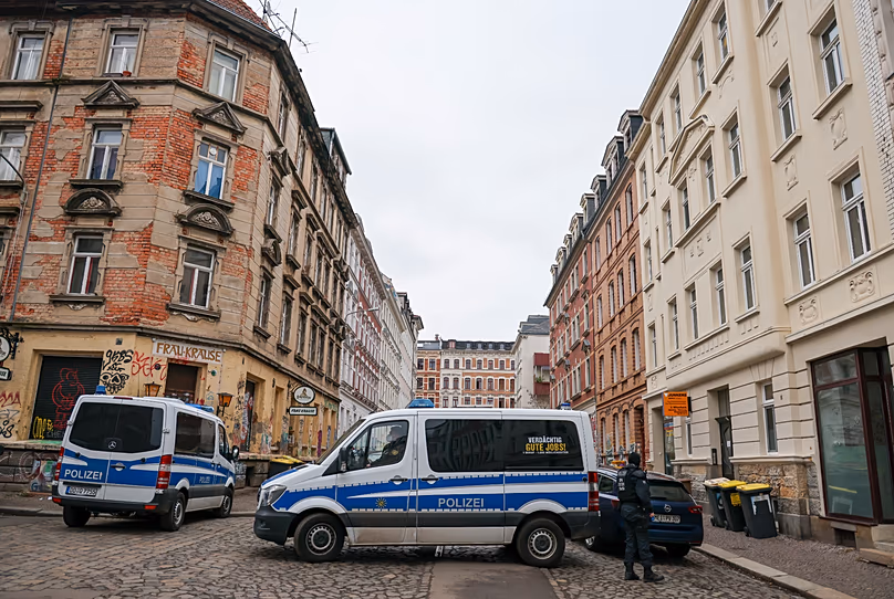 Police vehicles and officers stand during searches in the Connewitz district of Leipzig, 26 January, 2022