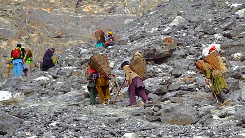 Porters travelling up to glacier grafting site, carrying ice pieces in wooden baskets on their backs.