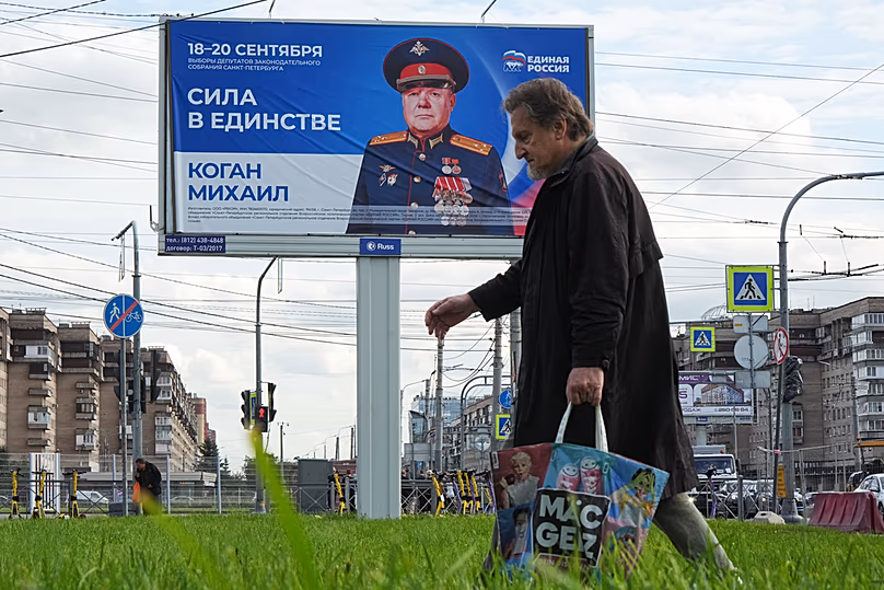 In Saint Petersburg a man walks past a billboard urging people to vote for a candidate from the United Russia party