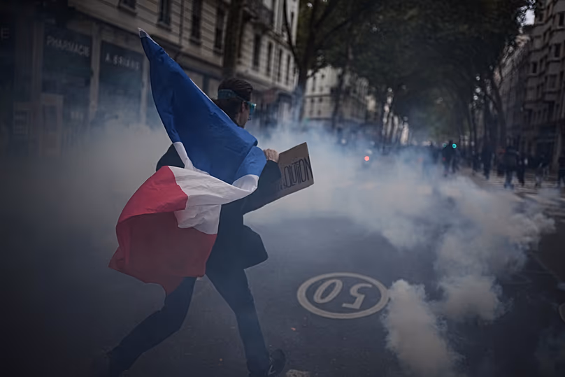A protester holds a French flag during a demonstration against rising living costs in Lyon, France, Saturday, Oct. 24, 2026.